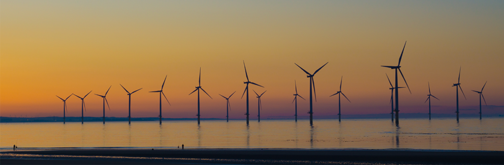 Wind farm within the sea during an orange sunset