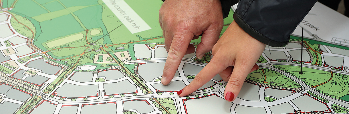 Two people pointing at a map on a table.